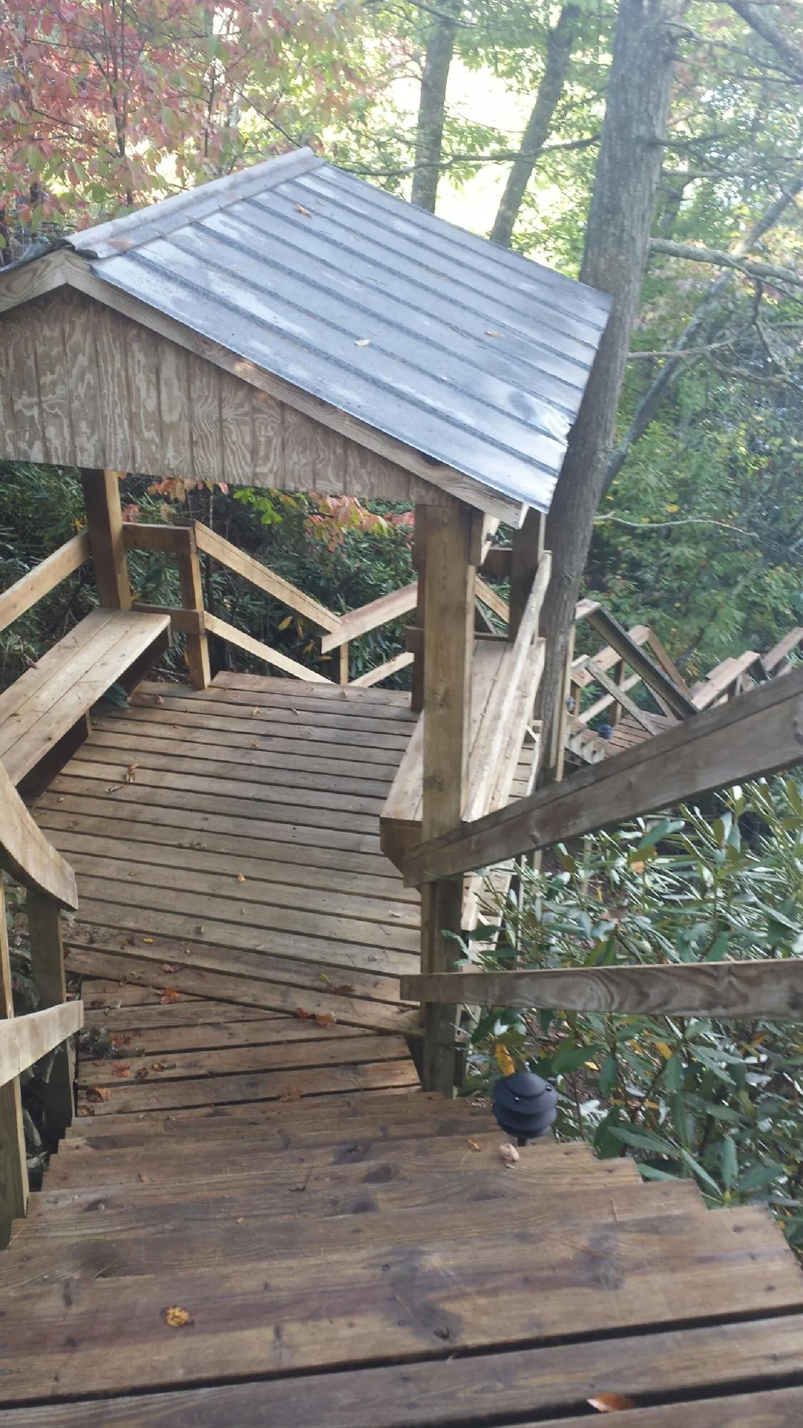 Metal roofed shelter over wooden steps on a wooded walkway — Skylight Repair & Installation work by our crew in Amity