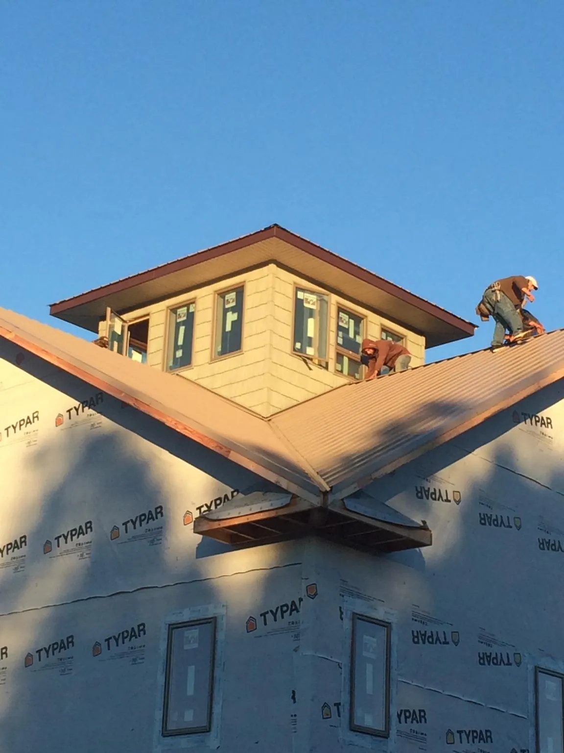 Roofers working around a rooftop cupola on a new metal roof at sunset — Roof Waterproofing in Amity by Roofing Brothers